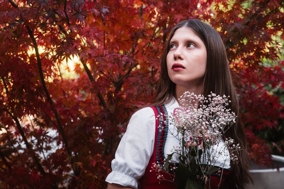 Kvinna i traditionell bayersk dirndl med höstlöv i bakgrunden.